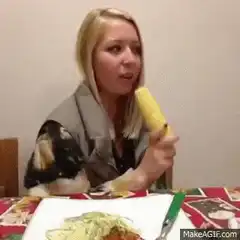 Woman eating corn with two people watching