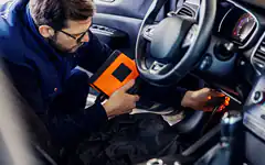 man using diagnostic tool in car