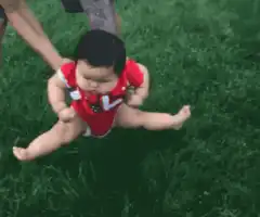 Baby doing splits on grass
