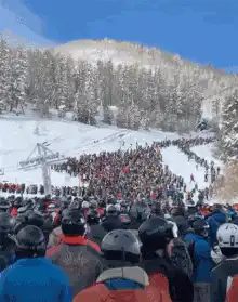 Crowd of skiers watching a snowboarder jump