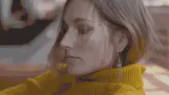 woman in yellow sweater looks up