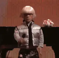 Man in silver vest and blonde wig dancing