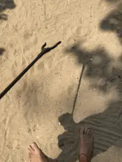 person holding a black stick on sand
