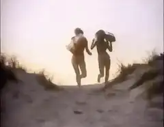 Two women running up a beach dune