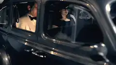 Man and woman in tuxedo and sunglasses in car