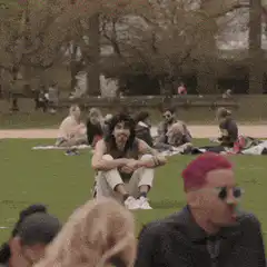 Guy sitting in park watching people making friends