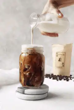 pouring milk into iced coffee