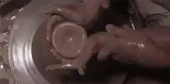 Hands shaping clay on a pottery wheel