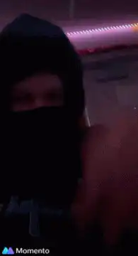 Person in black hoodie and mask waving hand