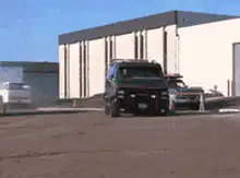 Black GMC van drifting in dirt lot
