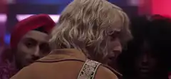 Blonde man looks back with a confused expression