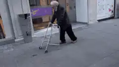 Old man with walker walks backwards