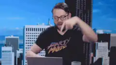 Man in Party Mode shirt pointing at laptop