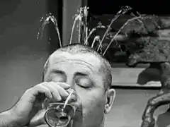 Man drinking water fountain from head