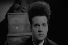 Man with wild hair stares intensely