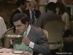 Mr Bean eats with a napkin tucked in his collar