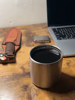 Coffee cup on desk with laptop and knife
