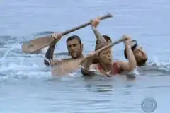 Survivor contestants rowing in water