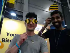 Two men wearing bee-themed accessories at a convention