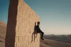 Man sitting on chair on cliff edge
