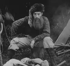 Bearded man sitting by campfire