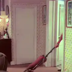 Mustache man in pink top vacuuming
