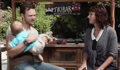 Man hands baby to woman