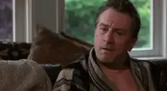 Robert De Niro smirking on a couch