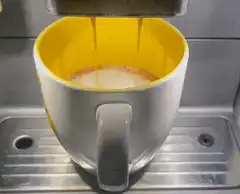 Coffee pouring into yellow mug