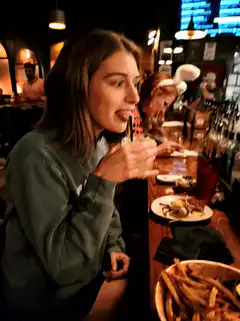 woman sips drink and smiles at bar