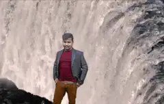Man standing in front of waterfall