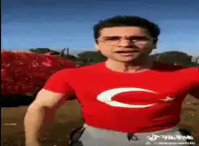 Man in Turkish flag shirt dances near red car