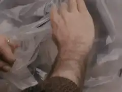 Hand opening plastic bag to reveal woman