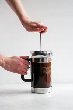 Hand pressing French press coffee plunger