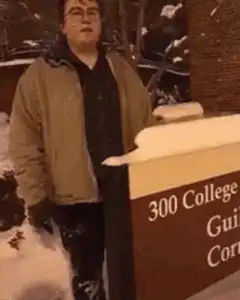 man falls into snow pile behind sign