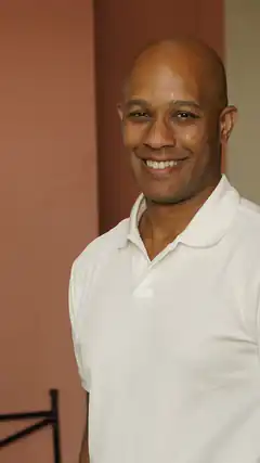 Bald man in white polo shirt smiling