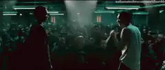 Two men facing off in a crowded underground fight club