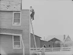 Man climbs ladder and kisses woman