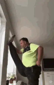 Man stretches leg on wall then pants drop