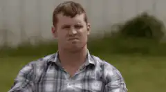 Man squinting in plaid shirt