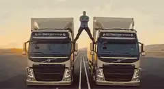 Man straddles two trucks