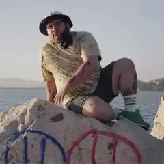 Man on rock lifts leg and sticks tongue out