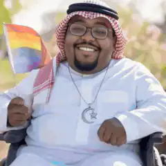 Man in wheelchair waving rainbow flag