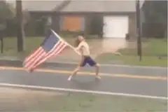 shirtless man running with american flag in rain