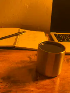 metal cup on desk with notebook