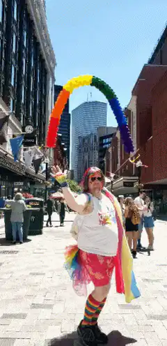 Person holding rainbow balloon arch