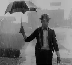 Charlie Chaplin walking in the rain with an umbrella