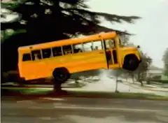 Yellow school bus flying over suburban street