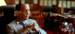 Tony Montana sitting with hands clasped