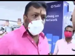 Man in pink shirt pointing at sign
